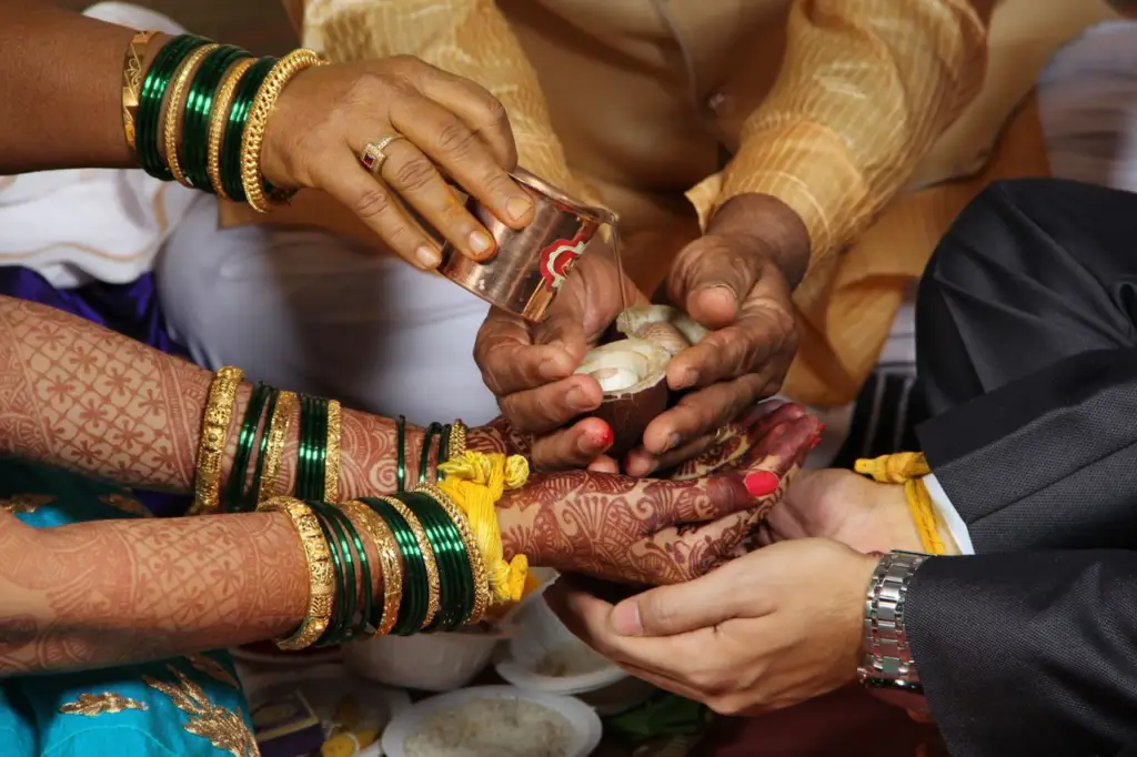 About Close-up of a Hindu wedding ceremony showing hands adorned with henna and traditional jewelry.